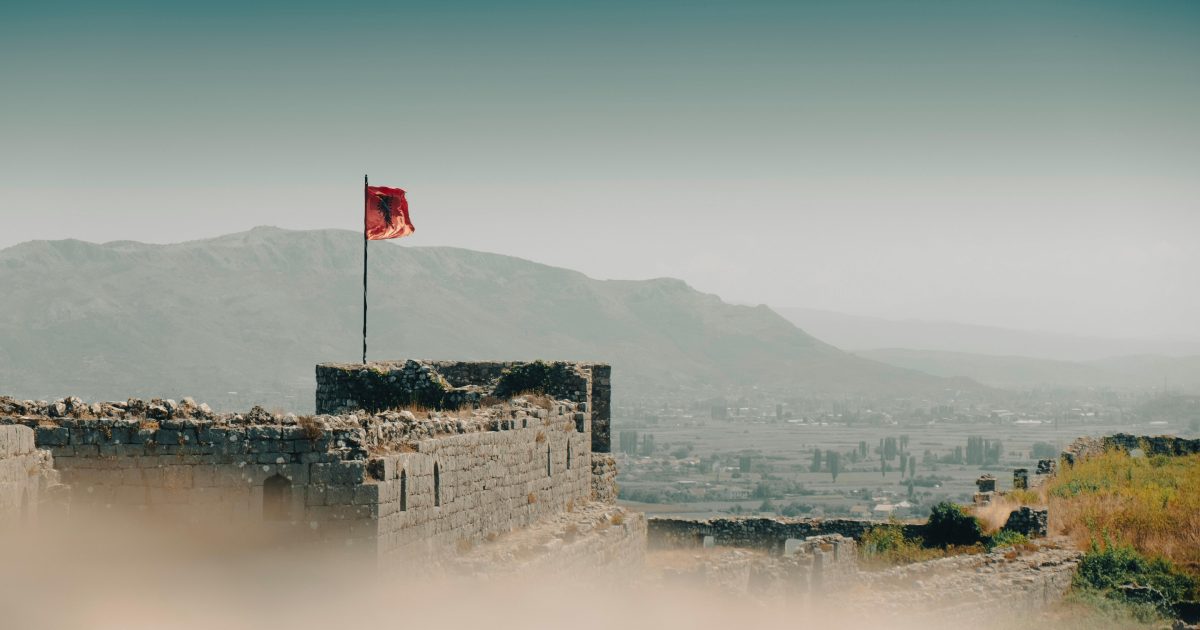 albania flag - Journey Inspirations rozafa castle in albania, with the albanian flag and mountains