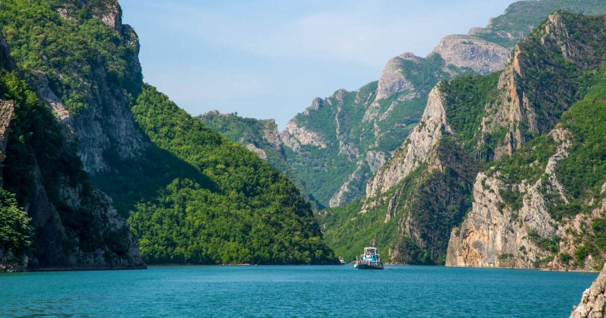 komani lake - Journey Inspirations lake koman in albania, blue water with a bot and green mountains allover