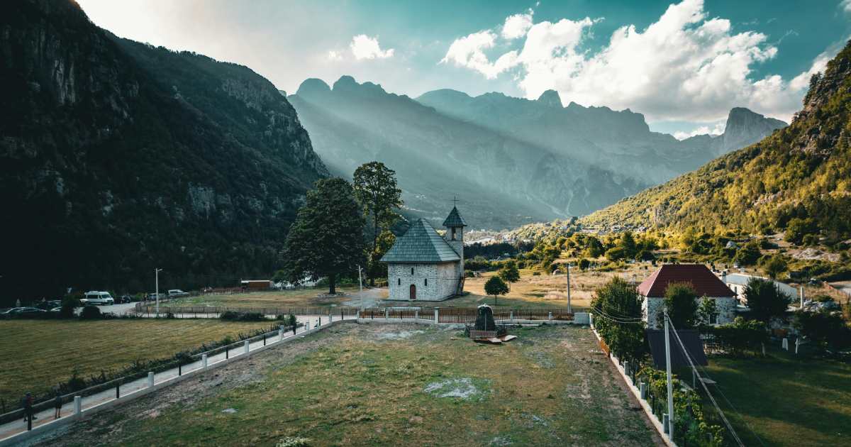 northern albania - Journey Inspirations theth national park in albania, a house made of stone and mountains with rays of sunshine